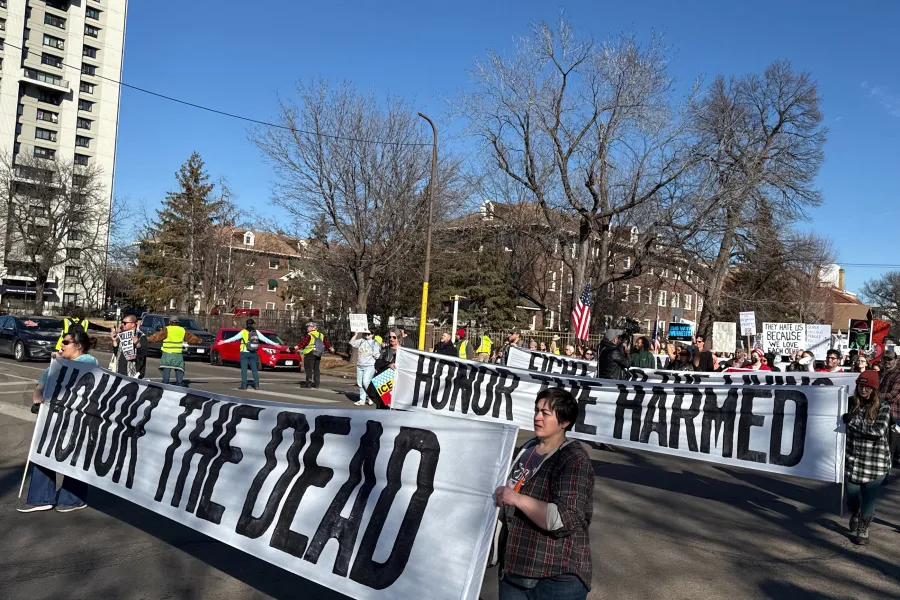 Photo of union members marching with banners that read "Honor the Harmed" and "Honor the Dead."
